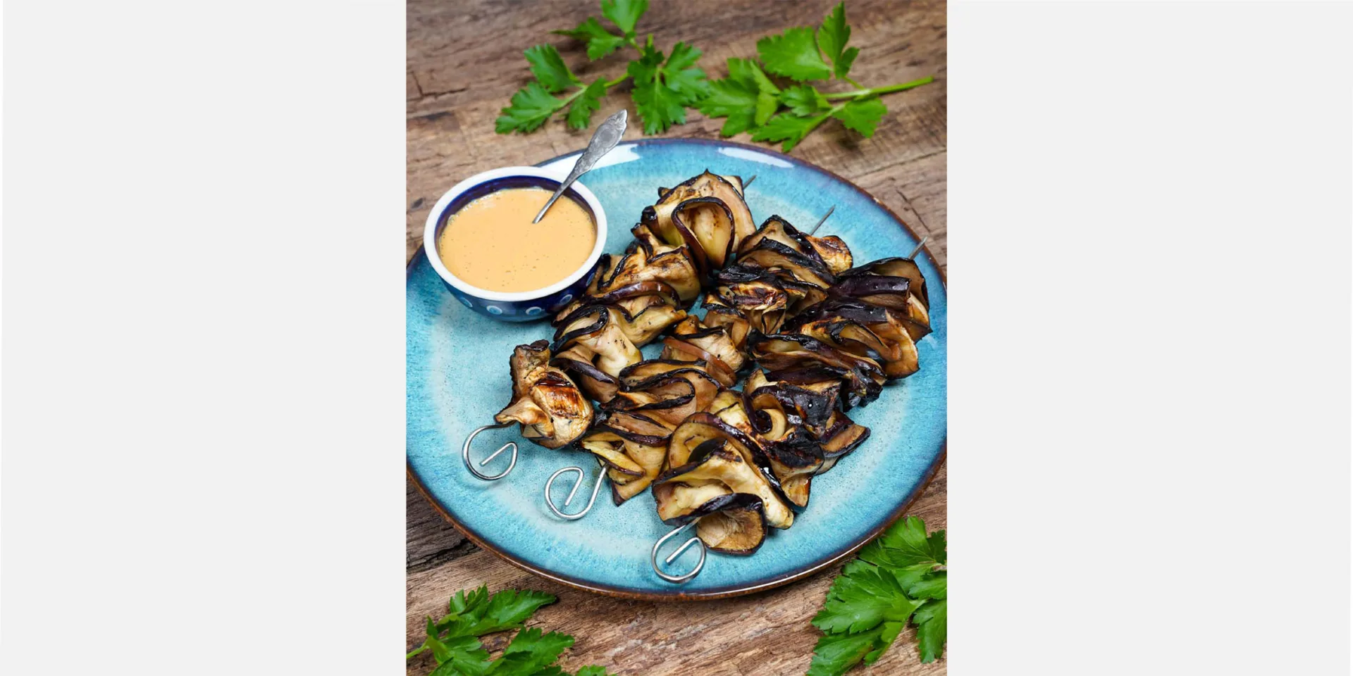 Auberginen-Sate auf einem Teller angerichtet, dekoriert mit veganer Erdnusssauce, hero
