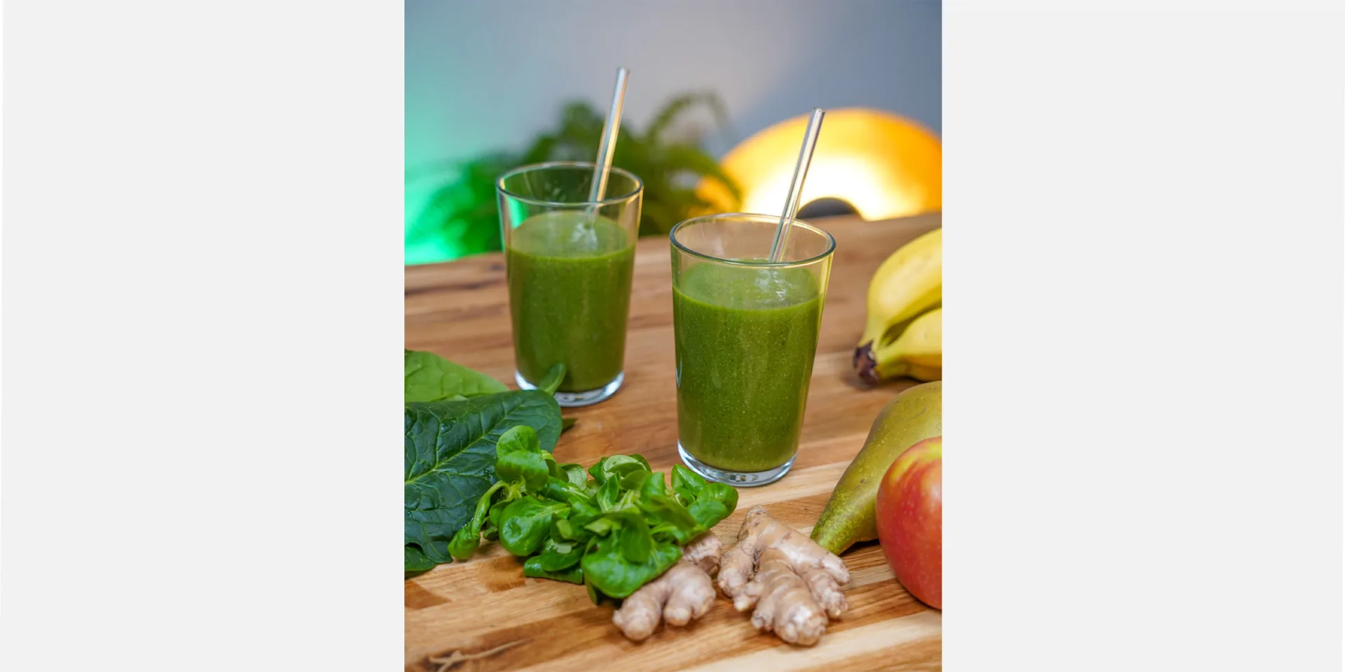 Grüner Smoothie vegan in zwei Gläsern gefüllt. Freundlich dekoriert mit den übrig gebliebenen Zutaten, hero 