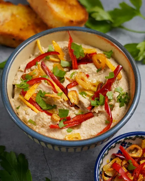 Hummus mit Aromaten vegan in einer Schüssel in der seitlichen Ansicht Teaser