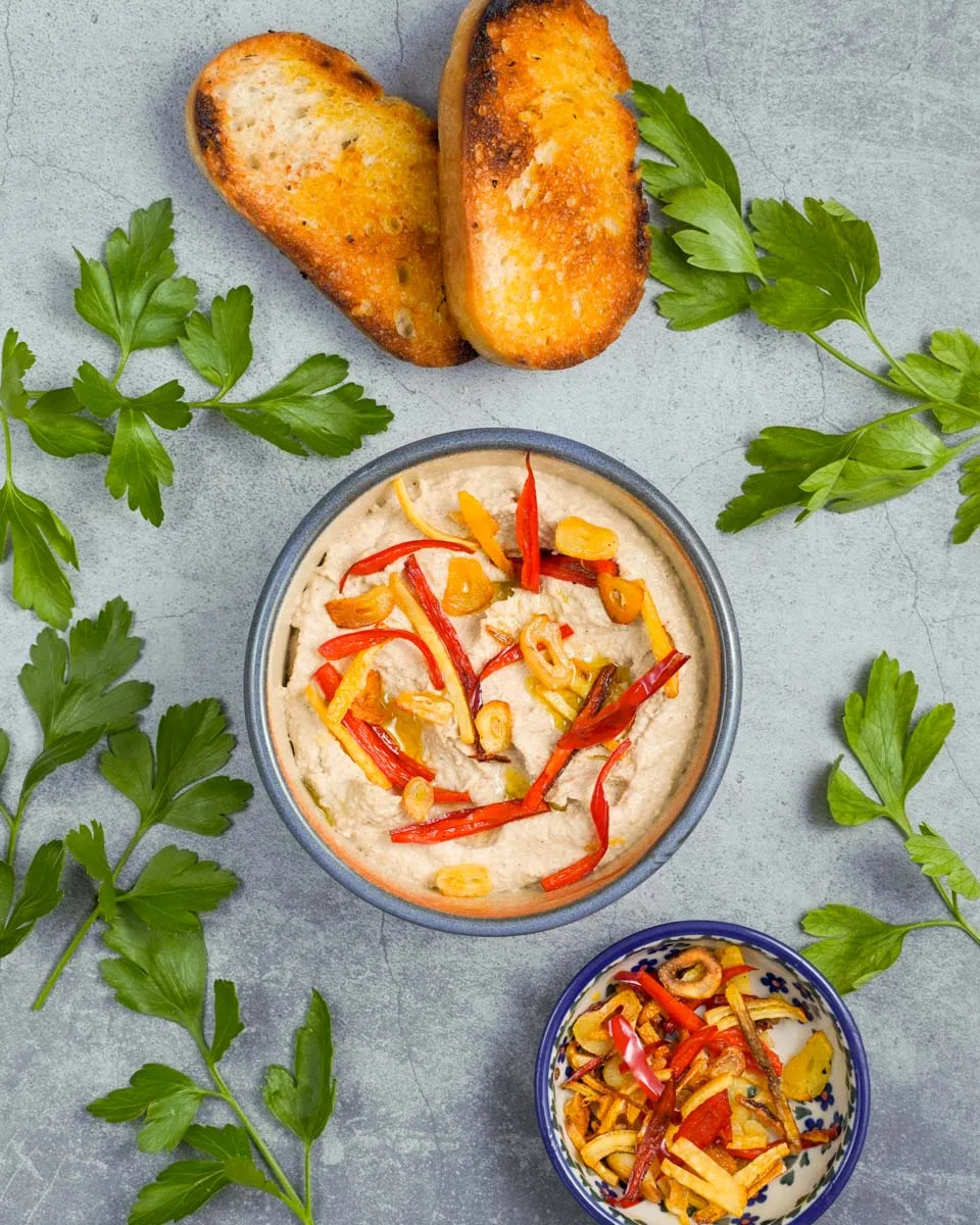 Hummus mit Aromaten vegan in einer Schüssel in der Draufsicht