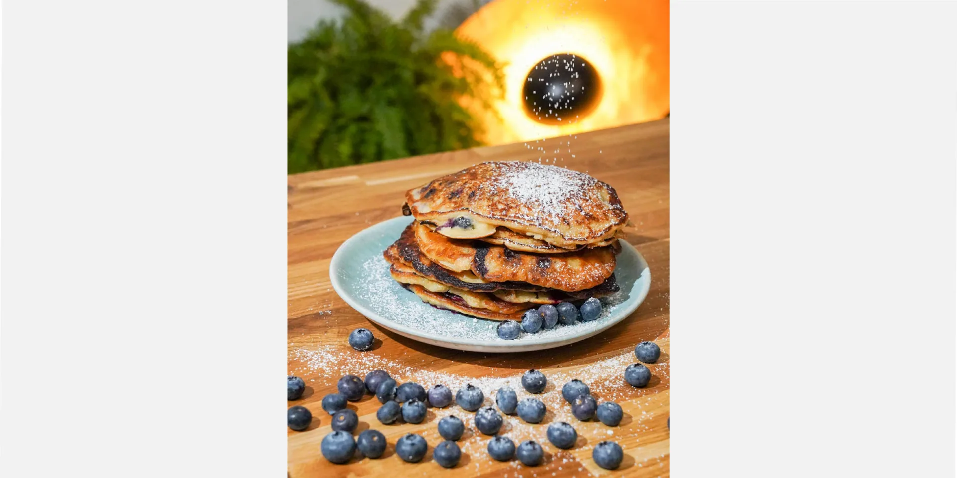 Vegan pancakes on a plate, decorated with blueberries and powdered sugar, hero