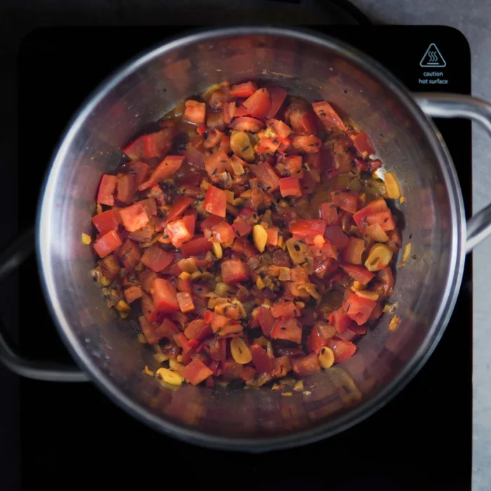 Vegan palak paneer, step 3. Onions, spices and tomatoes are fried in the pot.