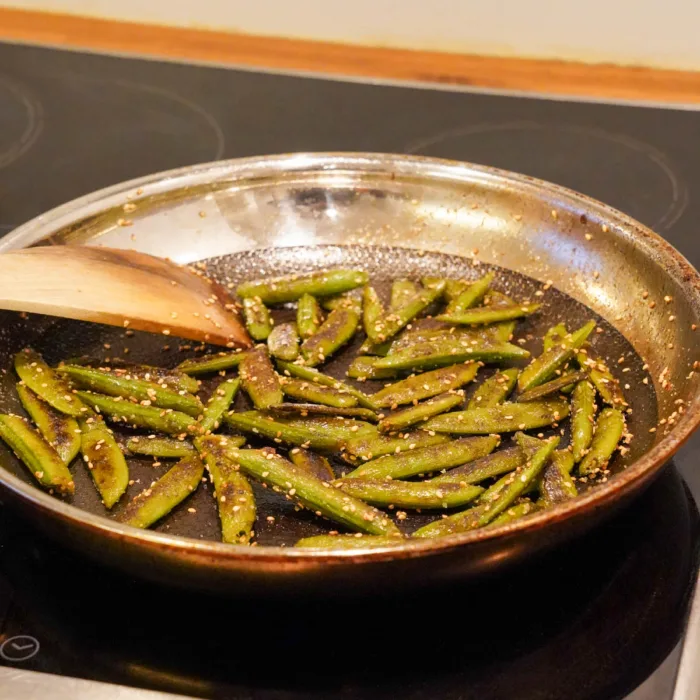 Snow peas being fried in the pan