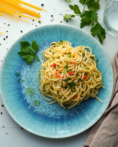 Spaghetti Aglio e olio auf einem bläulichen Teller angerichtet. In der Draufsicht. Hero