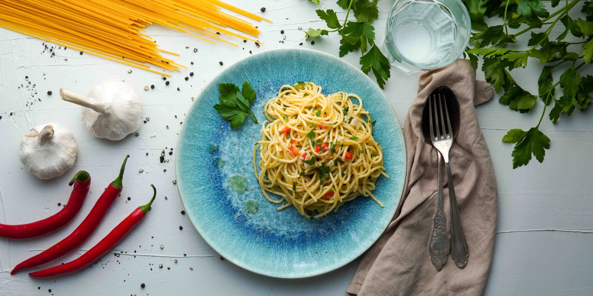 Spaghetti aglio e olio served on a bluish plate, seen from above. Hero