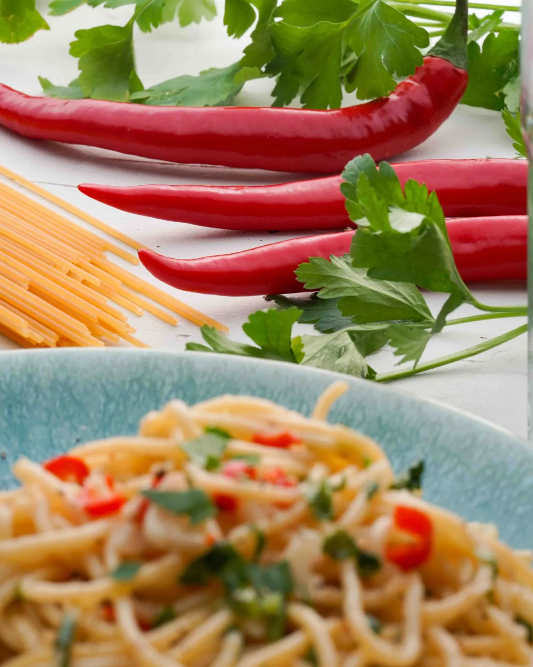 Close-up of a chili. In the foreground, vegan spaghetti aglio e olio
