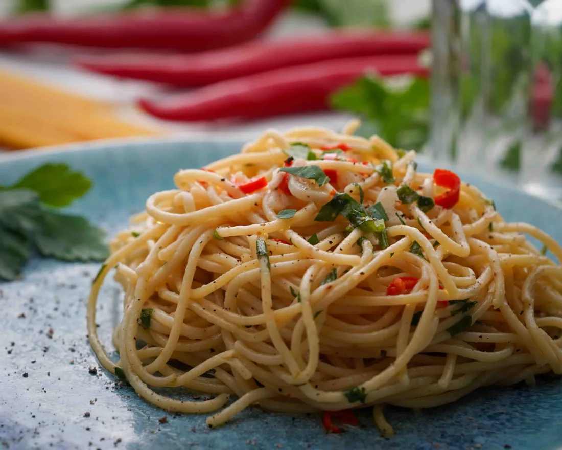 Spaghetti aglio e olio served on a bluish plate.