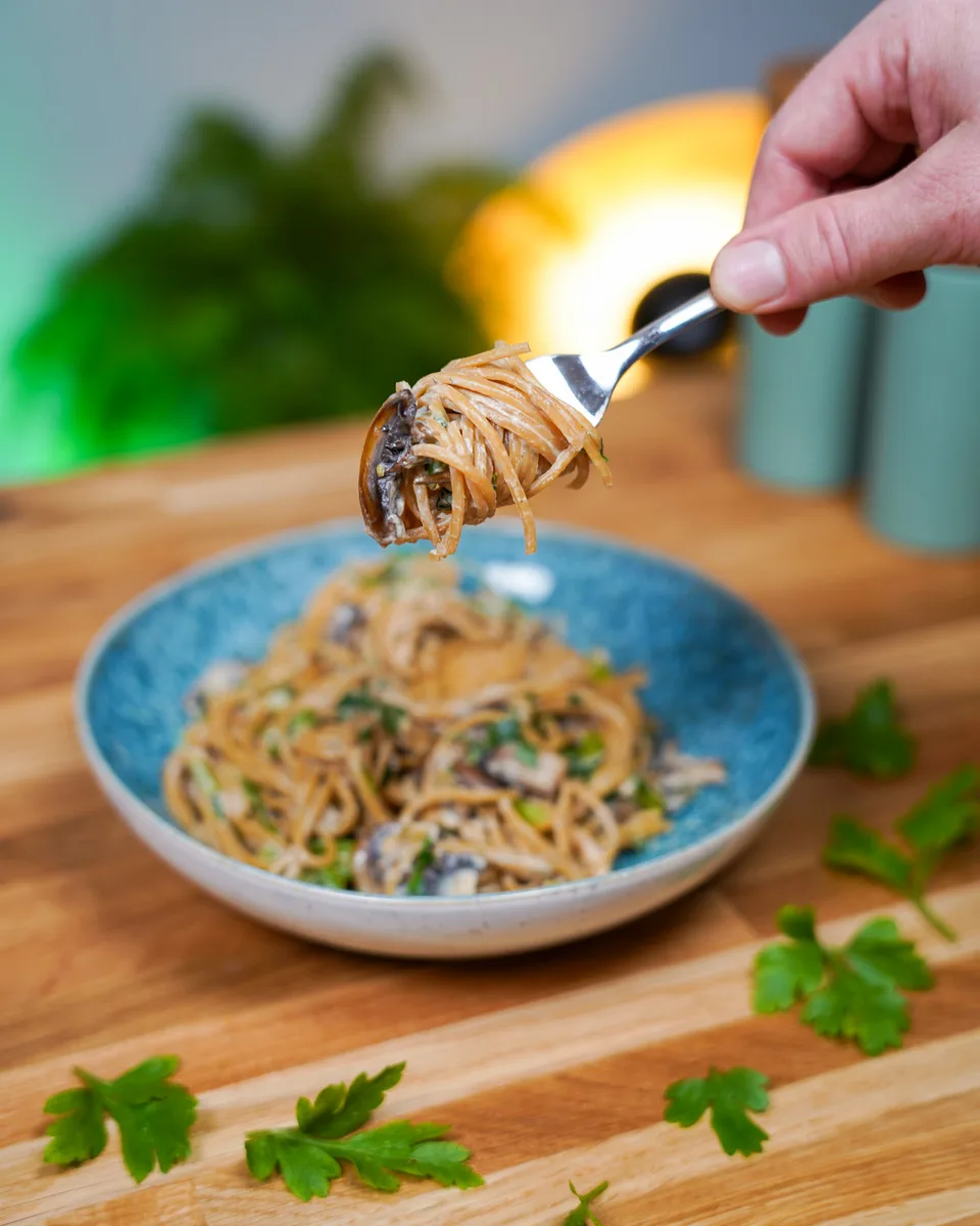 Spaghetti mit Champignonsauce vegan, Gabel mit umwickelten Nudeln in die Kamera gehalten, highlight