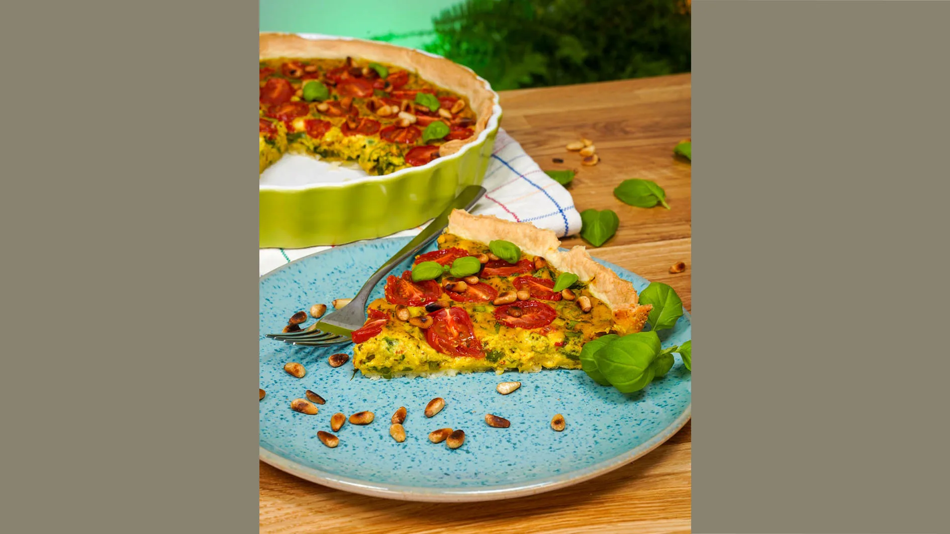 Vegane Quiche auf einem Teller angerichtet, mit Pinienkernen dekoriert, hero