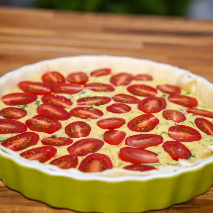 Quiche in eine Quicheform gelegt und Zutaten ineingefüllt
