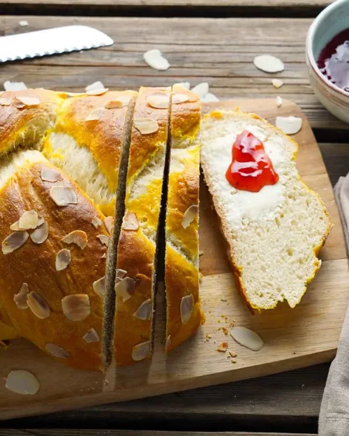 Osterzopf auf einem Brett, daneben vegane Butter und Marmelade  