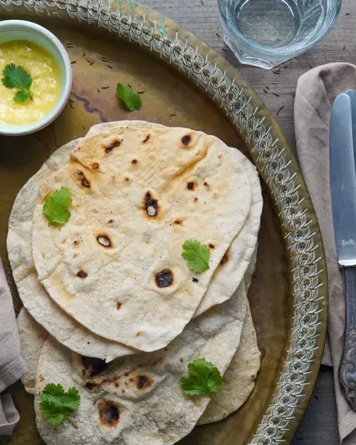Veganes Naan auf einem Blech, dekoriert mit Koriander, hero slider