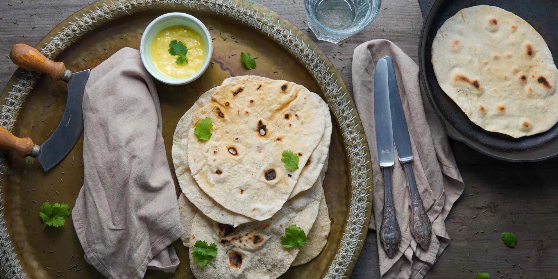 Vegan naan on a baking sheet, garnished with cilantro, hero slider
