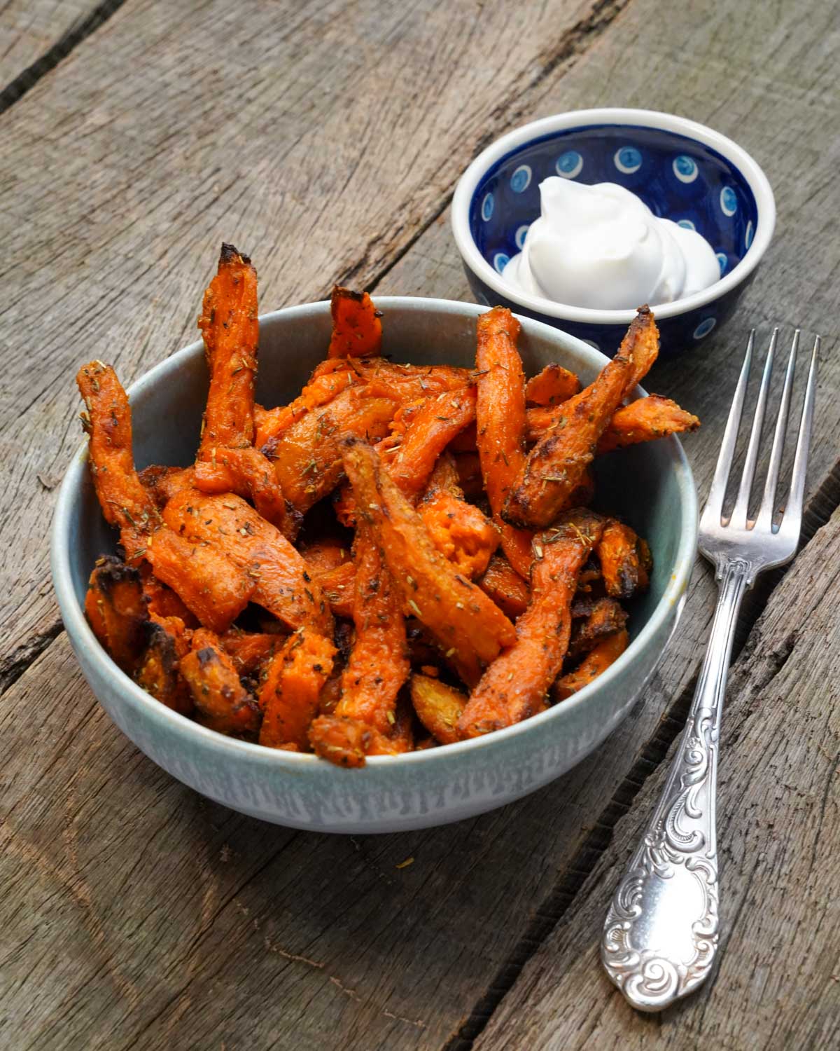 Seitlicher Blick auf Süßkartoffelpommes in einer Schüssel, daneben ein Dip