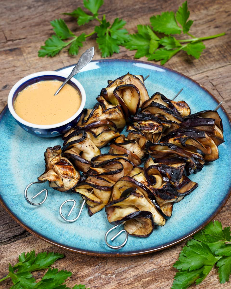 Auberginen-Sate auf einem Teller angerichtet, dekoriert mit veganer Erdnusssauce, teaser