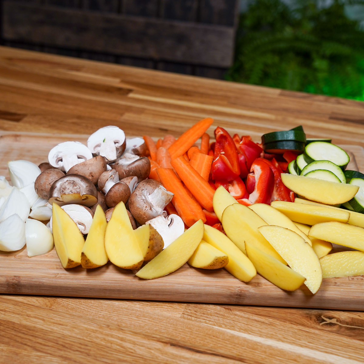 Zutaten für das vegane Ofengemüse kleingeschnitten auf einem Brett