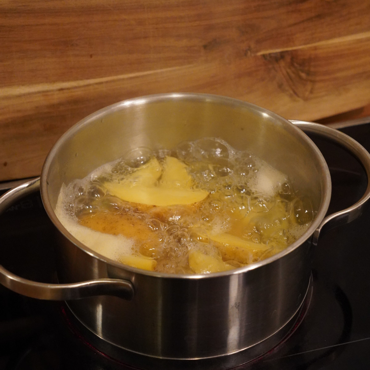 Kartoffeln werden in einem Topf vorgegart.
