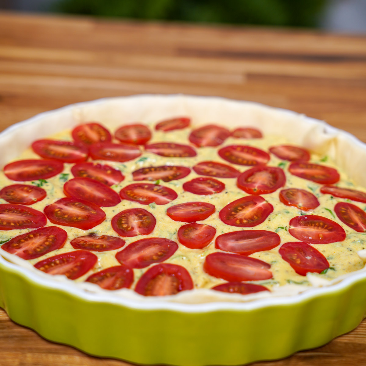 Quiche in eine Quicheform gelegt und Zutaten ineingefüllt