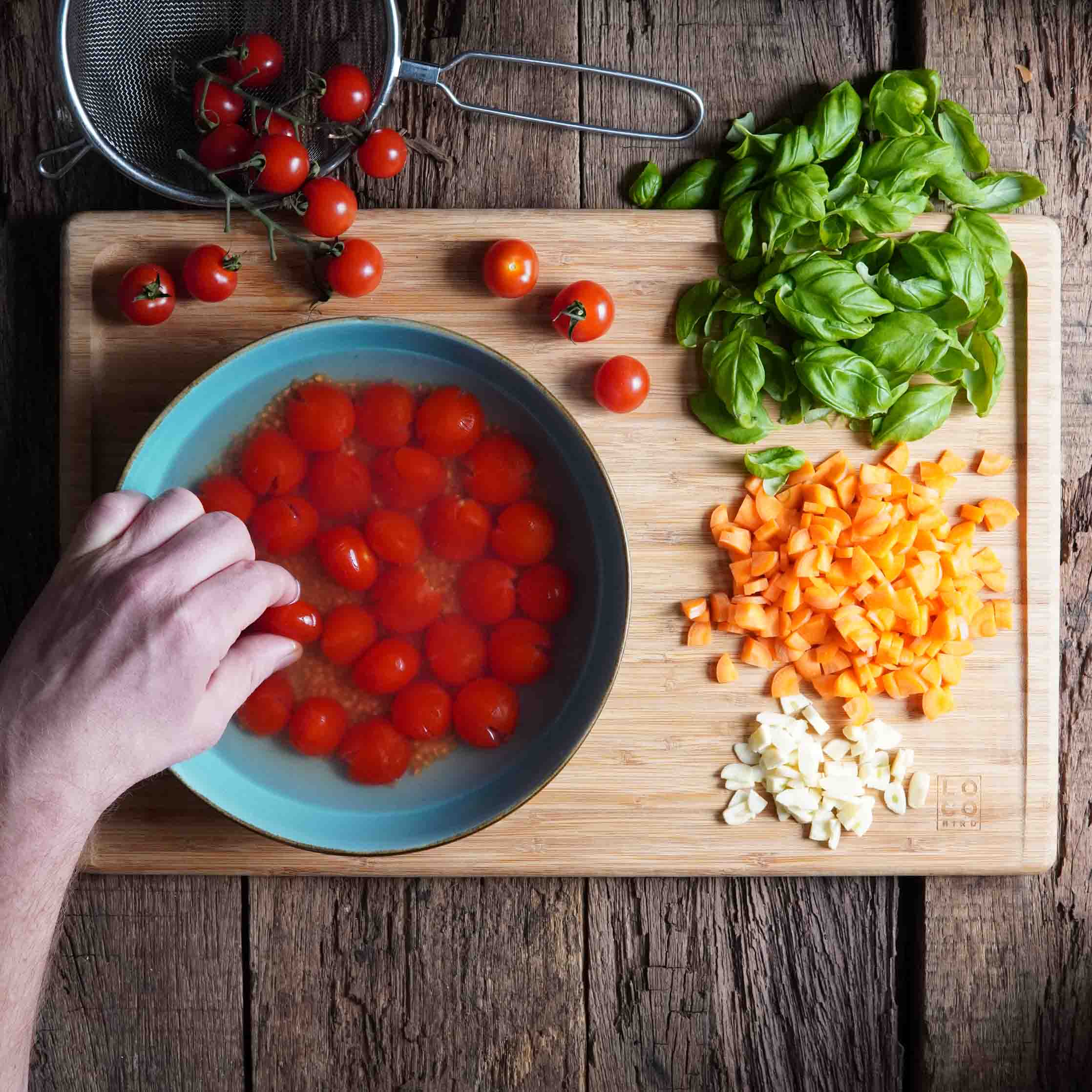 Spaghetti Pomodoro vegan. Schritt 1. Zutaten werden vorbereitet. Mit einer Hand werden Tomaten zerdrückt. Spaghetti Pomodoro vegan. Schritt 1. Zutaten werden vorbereitet. Mit einer Hand werden Tomaten zerdrückt.