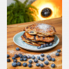 Veganer Pfannkuchen auf dem Teller, dekoriert mit Blaubeeren und Puderzucker, hero