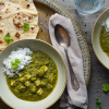 Vegane Palak Paneer in zwei Schüsseln, dazu Naanbrot, Wasser in der Draufsicht. Dekoriert mit frischen Zutaten wie Chili und Knoblauch.  