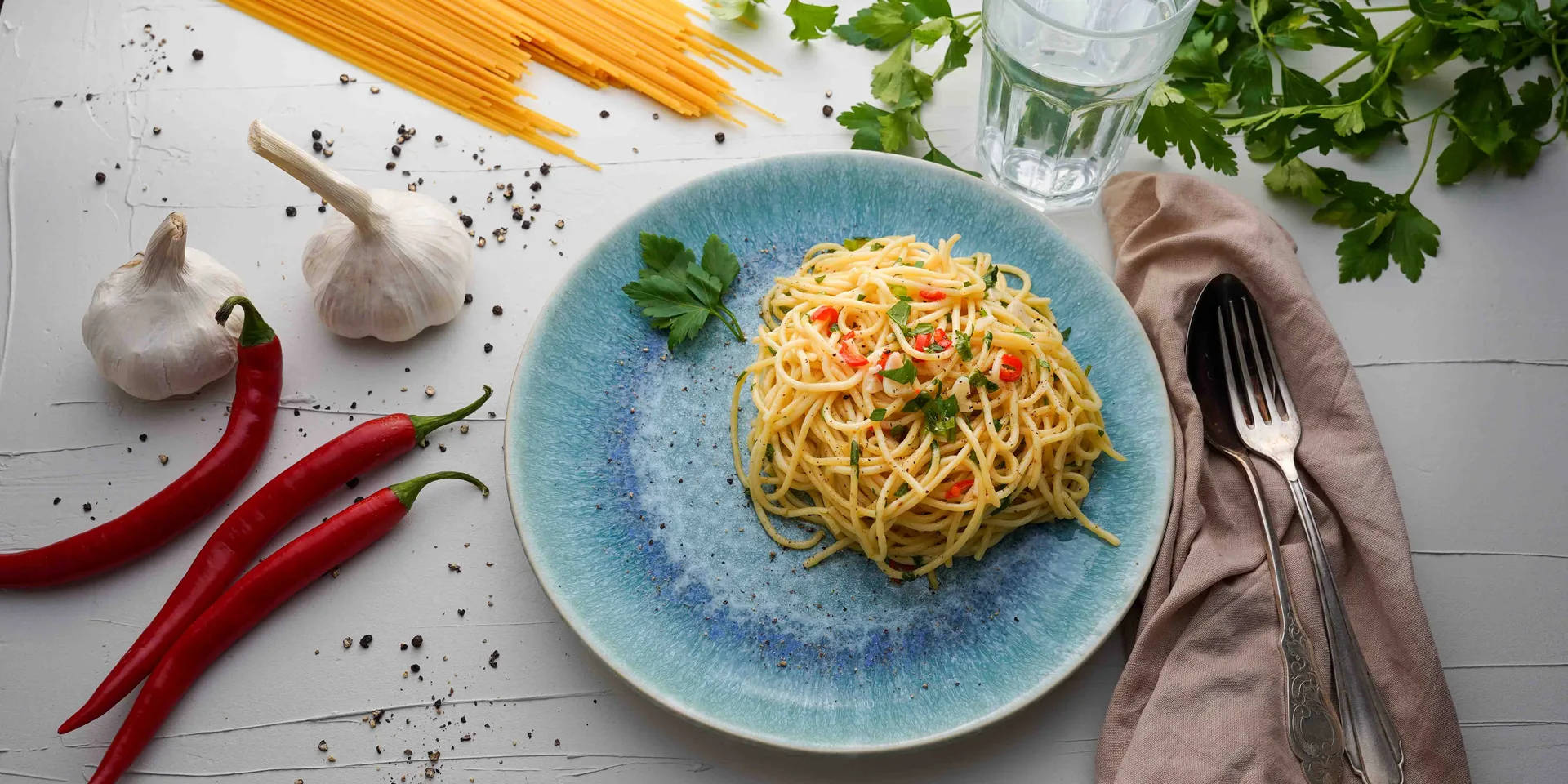 Spaghetti Aglio e olio auf einem bläulichen Teller angerichtet. Seitenansicht. Hero Slider