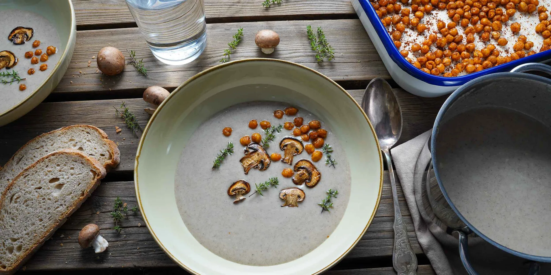 Vegane Champignoncremesuppe in der angewinkelten Draufsicht. Dekoriert mit Thymian und gerösteten Kichererbsen.